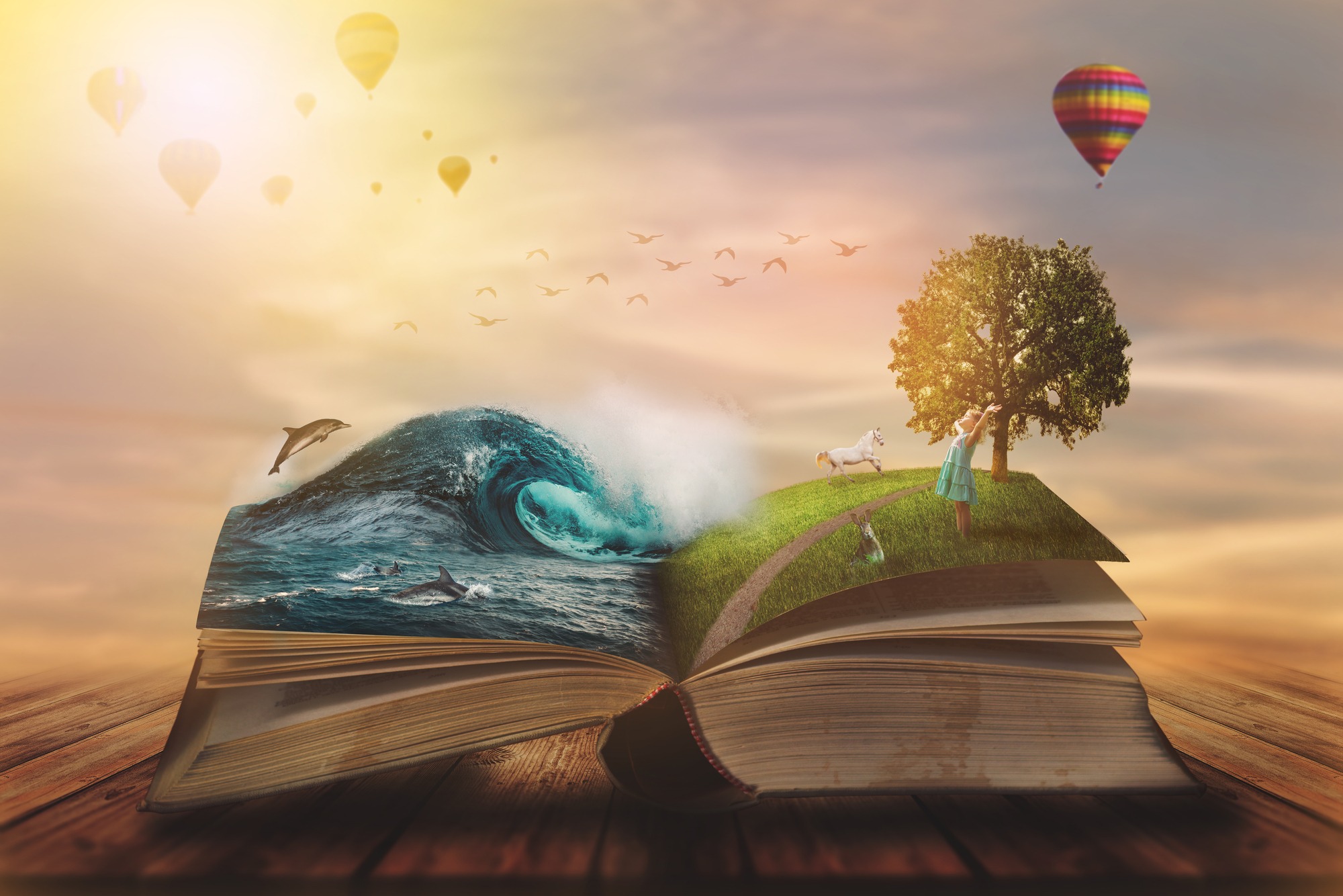 An imaginative scene unfolds from an open book with ocean waves, dolphins on one page, and a tree, woman, and unicorn under a serene sky with hot air balloons.